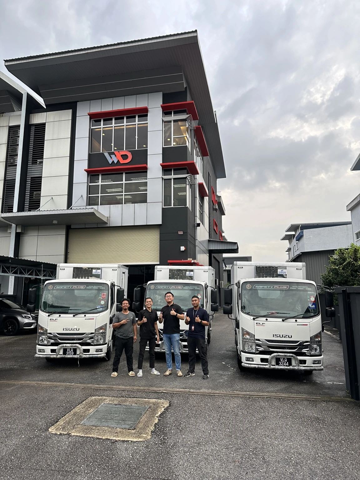 Customers and staff with several delivered Isuzu lorries
